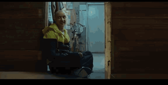 a man in a yellow and black jacket is sitting on the floor