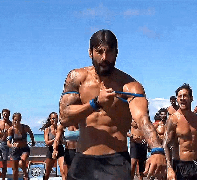 a shirtless man is holding a blue band around his shoulder
