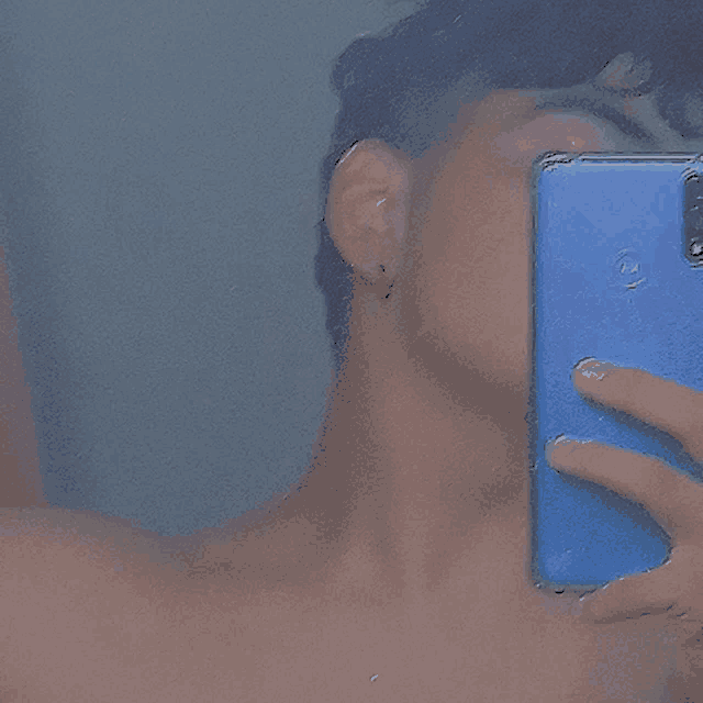 a man is taking a picture of himself with a blue cell phone