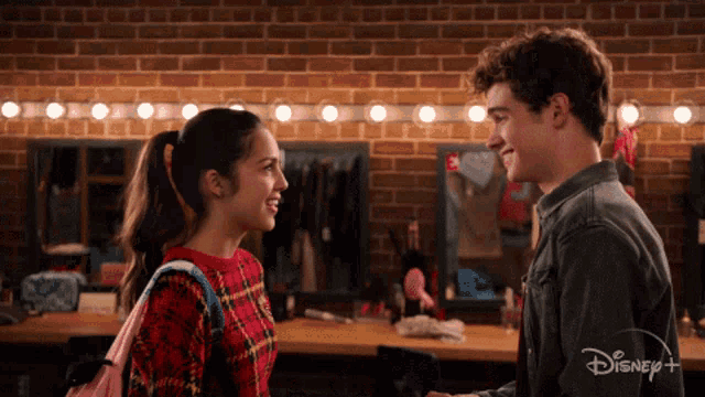 a boy and a girl are looking at each other in a room with a disney logo on the bottom
