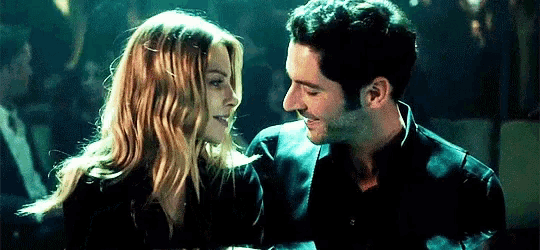 a man and a woman are standing next to each other and looking at each other in a dark room .