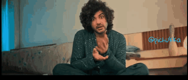 a man with curly hair is sitting on the floor in front of a bed with the hashtag @pichutka on the bottom