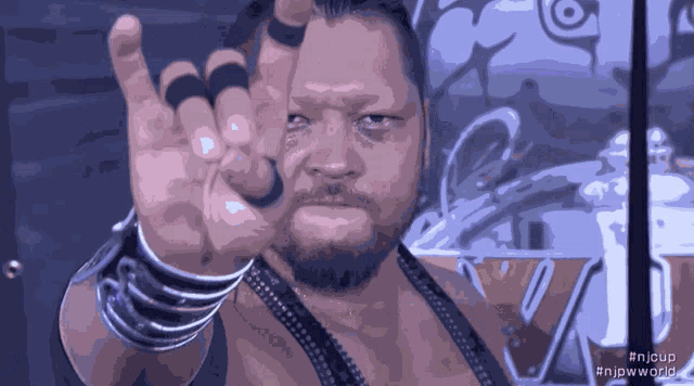a man with rings on his fingers is wearing a black vest