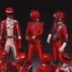 a group of red power rangers figurines are standing next to each other .