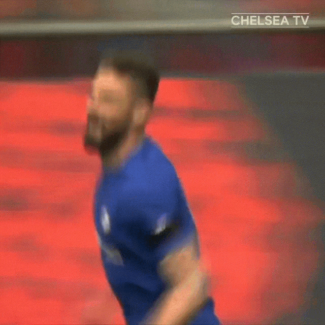 a man in a blue shirt is running in front of a chelsea tv logo