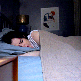 a woman is sleeping in a bed with a picture on the wall above her