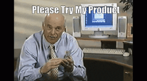 a man is sitting at a desk in front of a computer with the words please try my product above him
