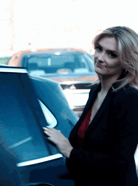 a woman is standing next to a car and smiling