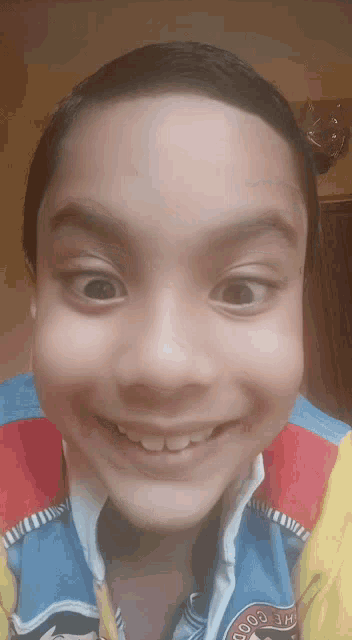 a young boy is smiling and wearing a jacket that says the good