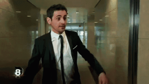 a man in a suit and tie is standing in a hallway with the number 8 on the wall .