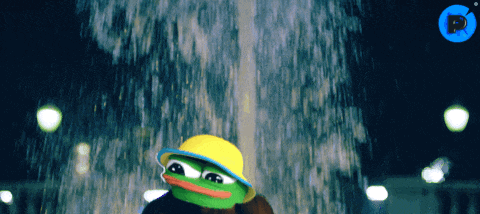 a frog wearing a yellow hat is standing in front of a fountain at night