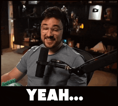 a man wearing headphones and glasses is sitting in front of a microphone and the word yeah is on the bottom