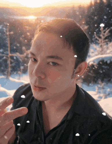 a man is making a peace sign in front of a snowy forest