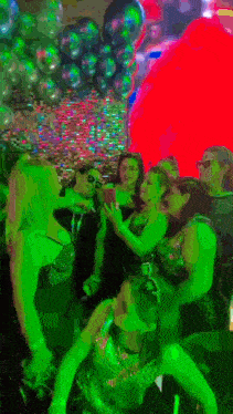 a group of women are dancing in a dark room with balloons in the background