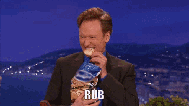 a man in a suit is holding a bag of chips and the word rub is on the screen