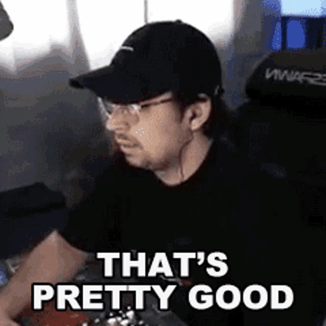 a man wearing a hat and glasses is sitting at a table and says that 's pretty good