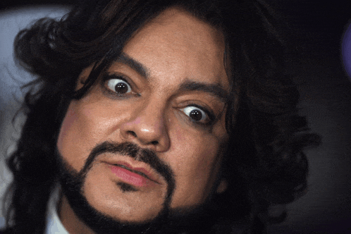 a man with long hair and a beard making a funny face