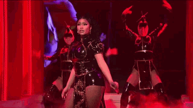 a woman in a black dress is singing into a microphone on a stage in front of a statue .