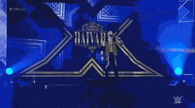 a man stands on a stage in front of a large x on a wall