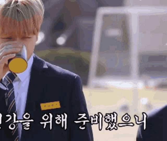 a man in a suit drinking from a yellow cup