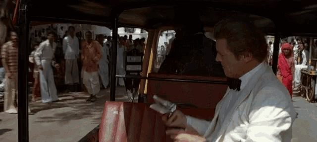 a man in a tuxedo sits in the back seat of a taxi