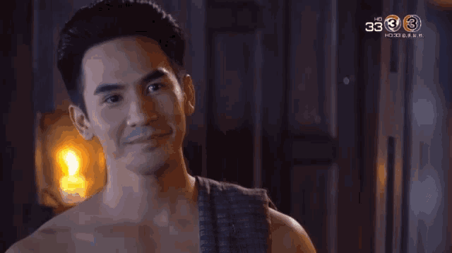 a man without a shirt is smiling in front of a tv screen that says 3333