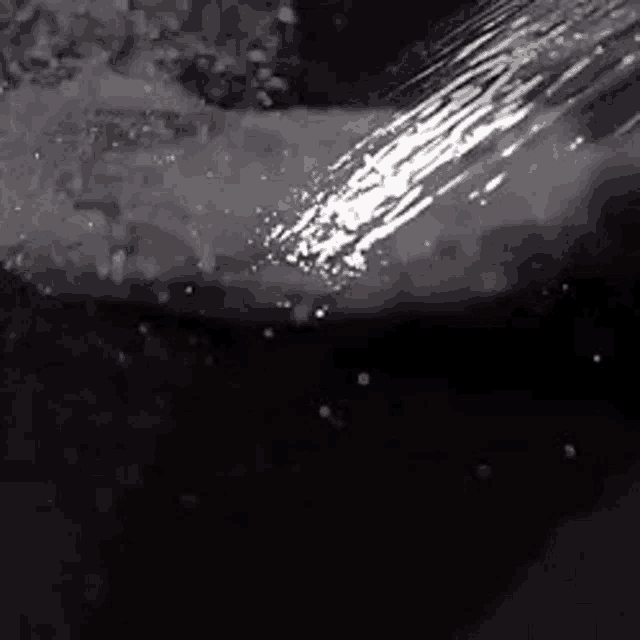 a close up of a shower head spraying water on a person 's arm .