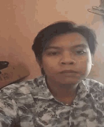a man is making a funny face while wearing a floral shirt .