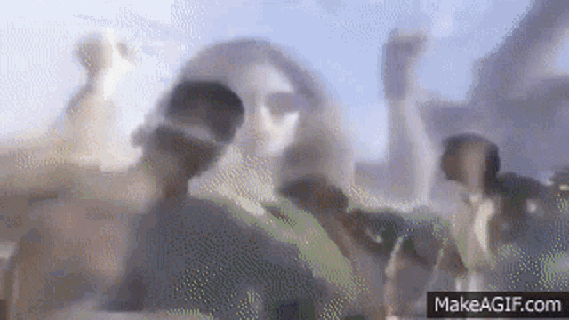 a blurry picture of a group of people standing next to each other with their hands in the air .