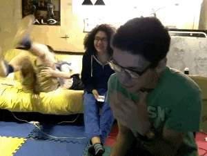 a man in a green shirt with the word sky on it is sitting in front of a woman laying on a bed .