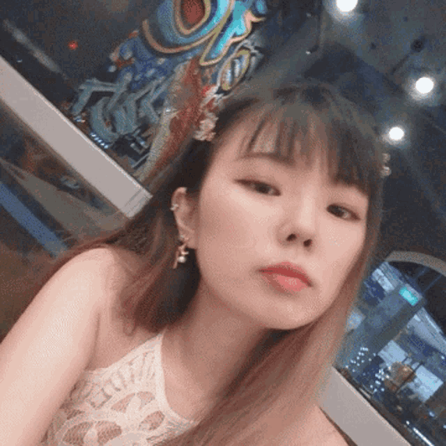 a woman wearing a halter top and earrings with the letter f on her ear is taking a selfie