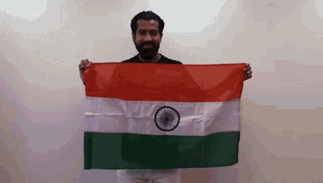 a man with a beard is holding an indian flag in his hands