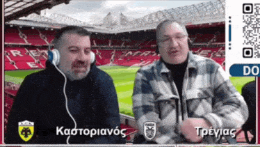 two men wearing headphones are talking in front of a soccer field with a qr code that says " do "