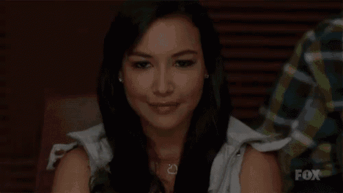 a woman is smiling at the camera while sitting at a table .