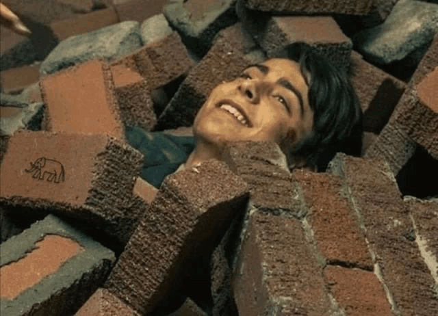 a man is laying in a pile of bricks with a brick that says ' para ' on it