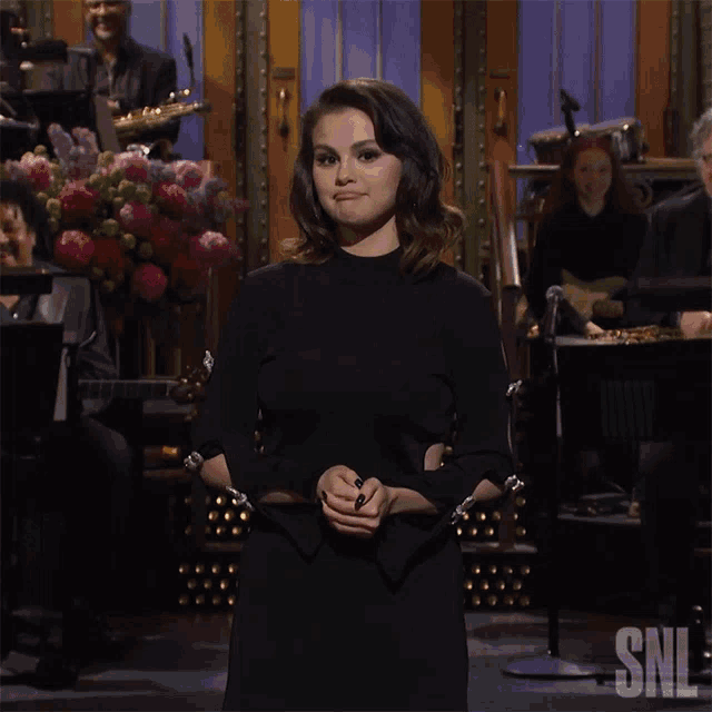 a woman in a black dress is standing in front of a sign that says snl