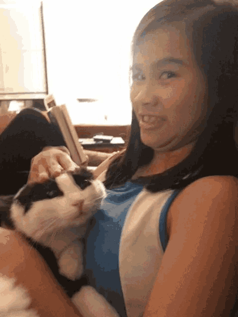 a woman is holding a black and white cat in her lap
