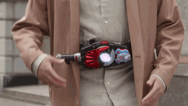 a man in a tan jacket is holding a belt with a red and blue light on it