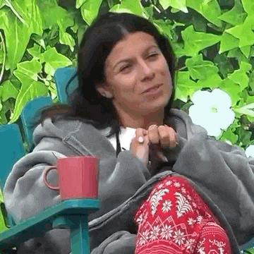 a woman is sitting in a chair with a cup on the arm .