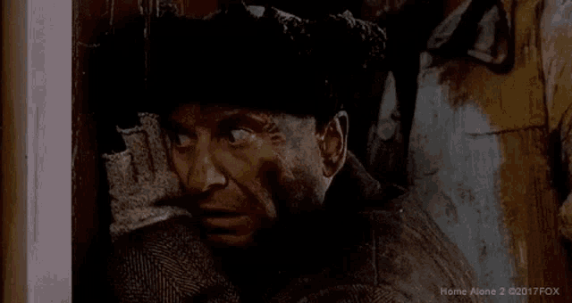 a man in a suit and hat is looking out a doorway .