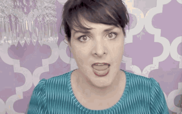 a woman making a funny face in front of a purple wall