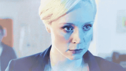 a woman with blonde hair and blue eyes looks at the camera