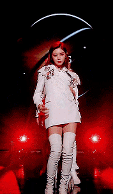 a woman in a white dress and white boots is standing on a stage