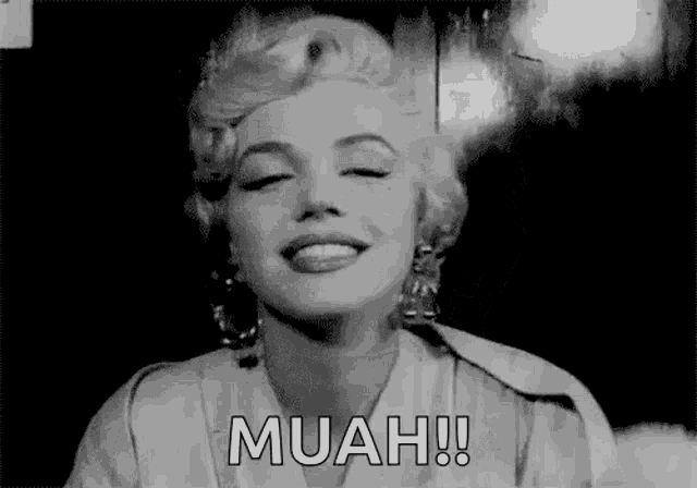 a black and white photo of marilyn monroe smiling with the words muah written next to her .