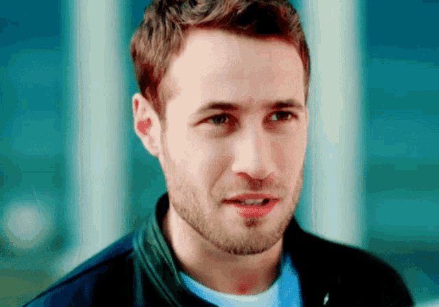 a man with a beard is wearing a black jacket and a white shirt