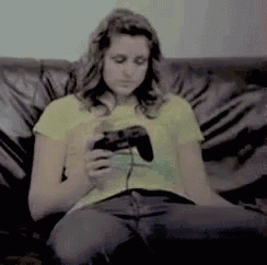 a woman in a yellow shirt is sitting on a couch holding a video game controller