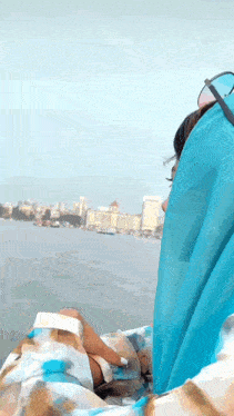 a woman in a blue scarf looks out over the water
