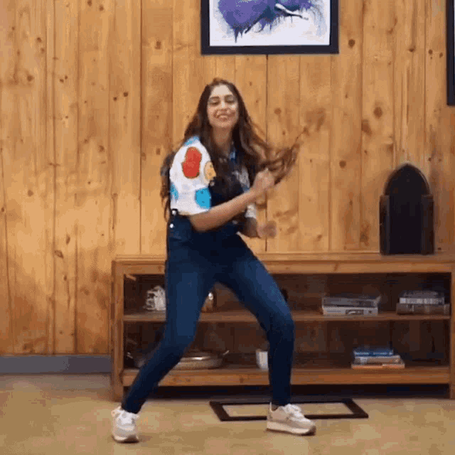 a woman is dancing in front of a wooden wall in a living room
