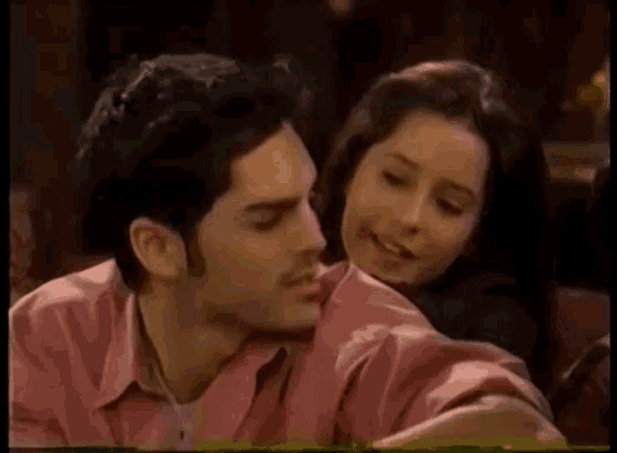 a man in a pink shirt is sitting next to a woman