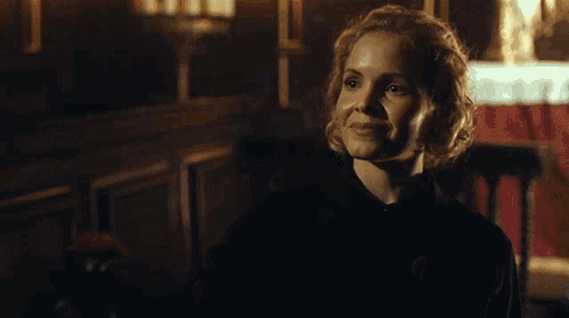 a woman in a dark room with a candle in her hand